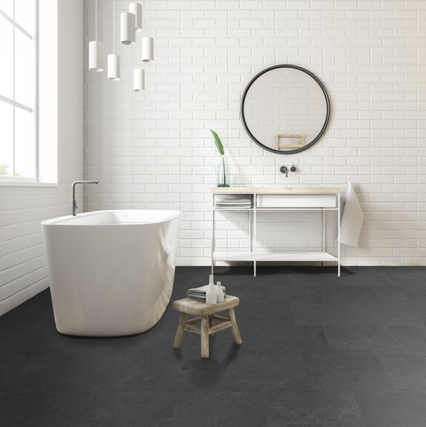 Moderne badkamer met witte bakstenen muur, vrijstaand bad en Armon Antraciet Nero rec 60x60cm keramische vloertegels. Luxe en minimalistisch design.