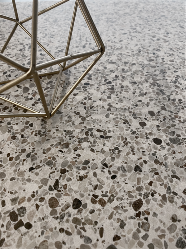 Close-up van Class Terrazzo Mira rec 60x60cm terrazzo tegels keramische met elegant gespikkeld patroon en decoratief metalen object, ideaal als vloertegels binnen.