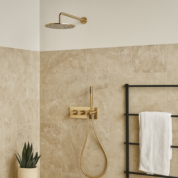 Ingebouwde thermostatische doucheset in geborsteld goud met regendouche, handdouche en wandmontage in een moderne badkamer met beige natuursteen tegels.