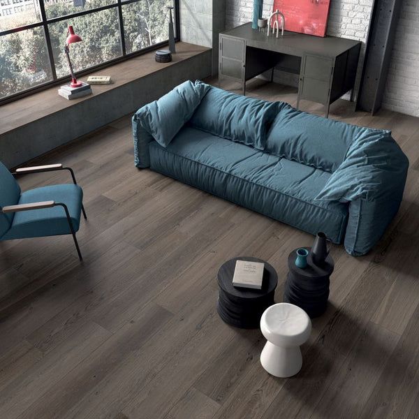 Moderne woonkamer met keramisch parket Poetry Mud 30x120 cm, gelegd in visgraatstijl met warme houttint en comfortabele blauwe bank.