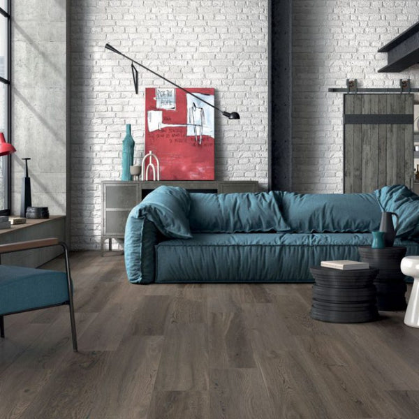 Woonkamer met keramisch parket Poetry Mud 30x120 cm in warme houtlook; modern interieur met blauwe bank en veel daglicht.