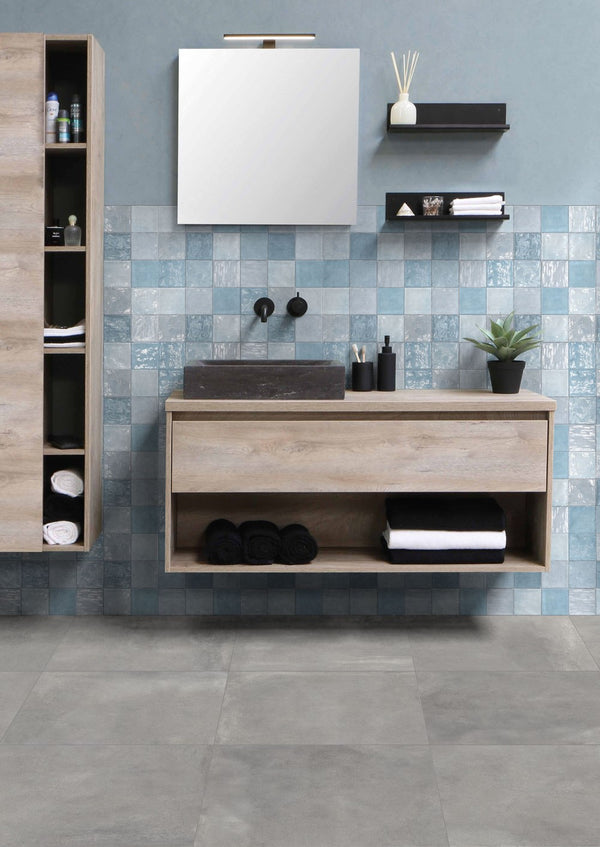 Mystone Fog grijze keramische vloertegels in een moderne badkamer met houten wastafel, blauwe wandtegels en strakke accessoires, ideaal voor badkamer en vloer.