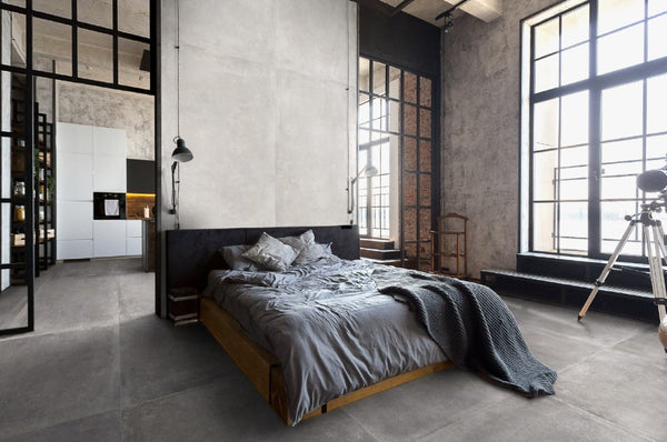 Industriële slaapkamer met grote ramen en betonlook vloertegels van Durstone White 120x260 cm, gecombineerd met een minimalistisch interieur en open doorgang naar de keuken