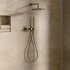 Moderne inbouw doucheset in geborsteld nikkel met regendouche, handdouche en thermostaatkraan, gemonteerd op een beige natuurstenen badkamerwand.