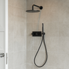 Moderne inbouw doucheset in gunmetal met regendouche en handdouche tegen een lichtgrijze betegelde badkamerwand.