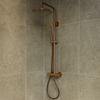 Moderne douchecabine met een luxe geborsteld bronzen regendoucheset, inclusief thermostaatkraan, handdouche en ronde regendouche, gemonteerd op natuursteenlook wandtegels.
