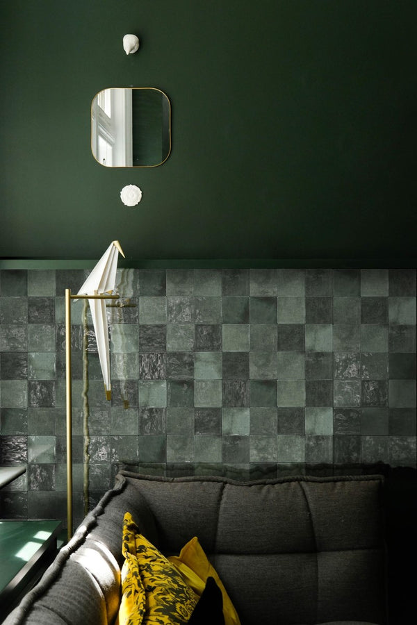 Vintage retro tegels Verde Oscuro Groen 10x10 cm verwerkt in een stijlvolle woonkamer met donkere wand, messing lamp en grijze bank